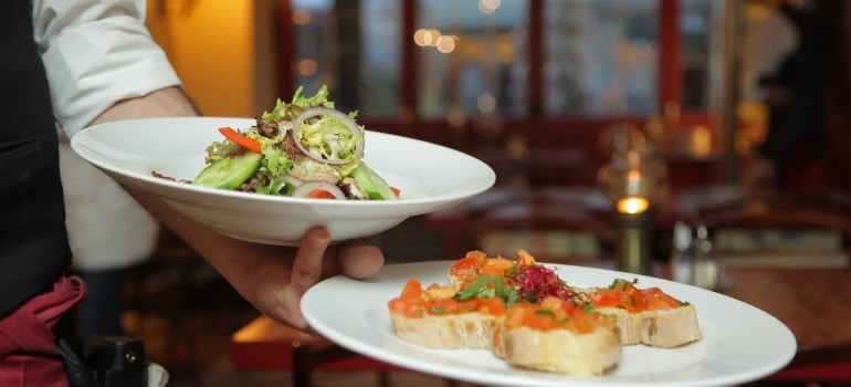 a waiter holding two plates with food