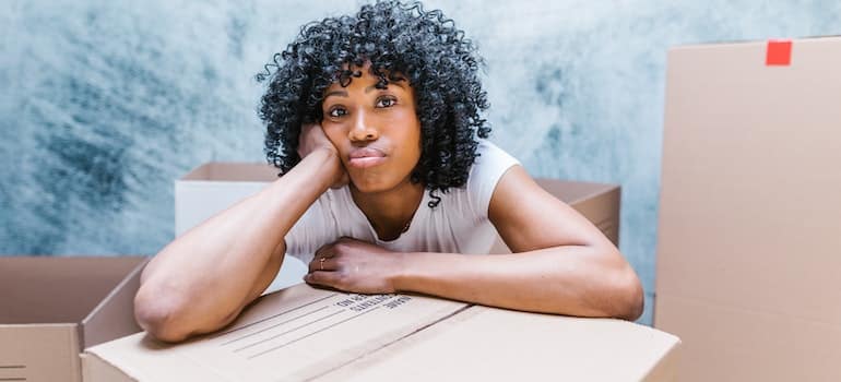 A girl sitting on a box while thinking about what to know when moving from Golden Beach to Coral Springs on short notice;