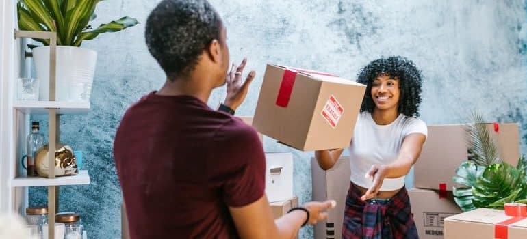 a man and a woman tossing cardboard boxes and probably discussing about how to treat your moving crew