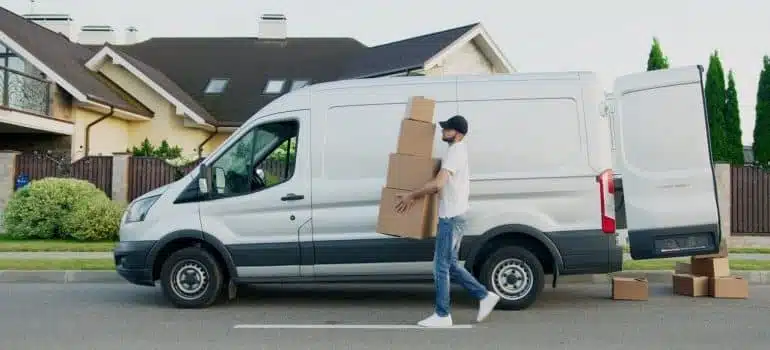 A mover carries boxes next to a white van