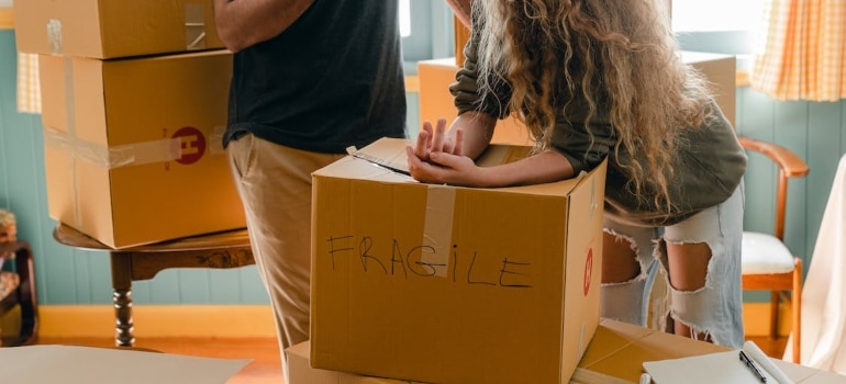 a couple surrounded by boxes labeled fragile about to get help when moving expensive wine collection in Miami