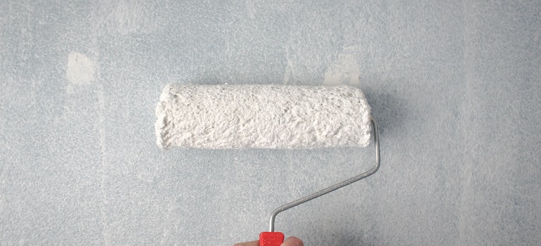 A person holding a paint roller on the wall as they renovate their Miami apartment.