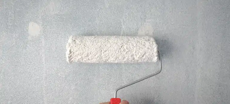 A person holding a paint roller on the wall as they renovate their Miami apartment.