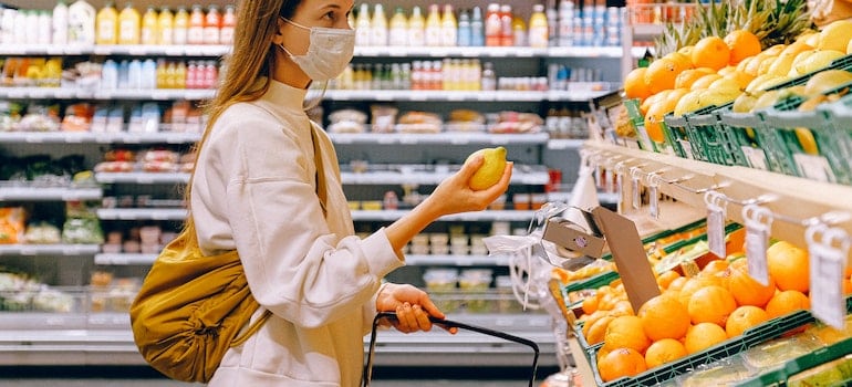 A woman looking at oranges in a supermarket as she shops for groceries.