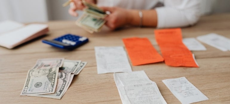a woman counting money while taking care of her bills before moving out