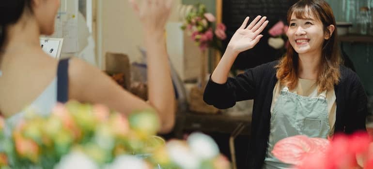 Happy female florist waving hand in shop