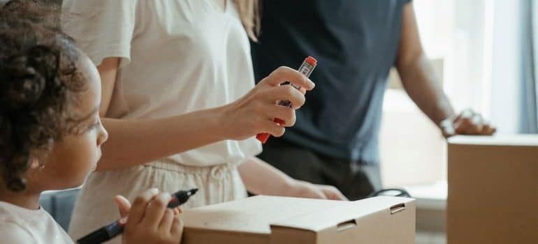 parents and a child labeling boxes