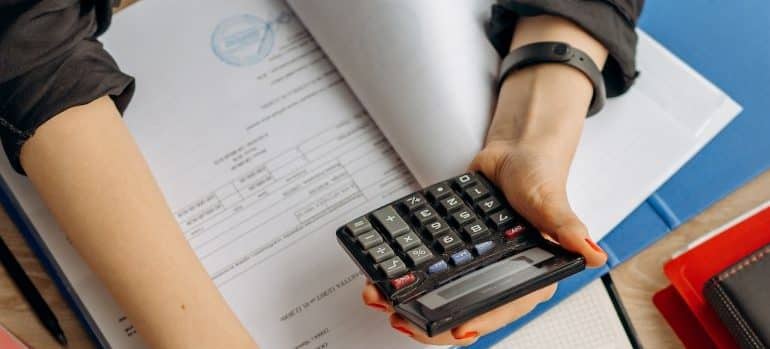 a woman holding a calculator and calculating before buying a beach house