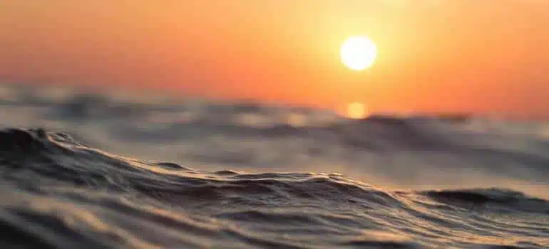 A shot of the ocean with the sun in the background