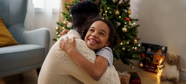 A little girl hugging her father during the holidays, as they spend time together in their house.