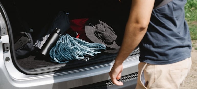 A man shows what to take out of trunk before things to pack in your car when moving cross country