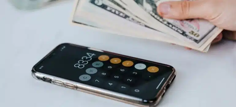 a person holding money and a phone with calculator on