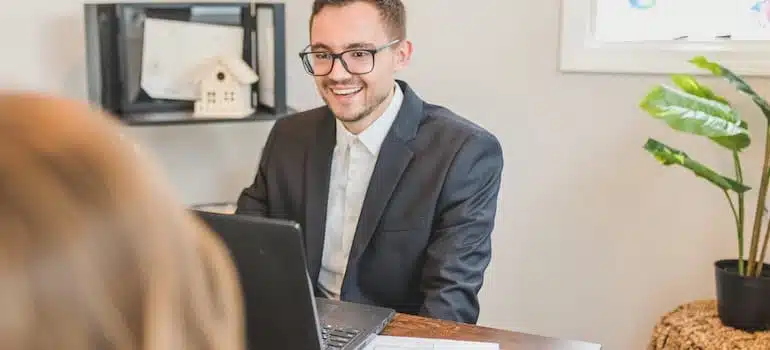 A broker smiling behind his office desk while trying to find a perfect office space in Miami