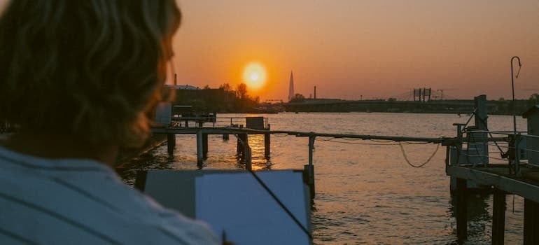A woman watching a sunset at the boardwalk while thinking about top 5 cities in South Florida for young adults;