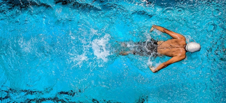 A people siwmming in a swimming pool, possibly in one of the Miami neighborhoods.