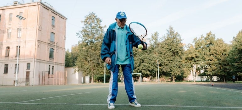 An older man holding a tennis racket, since one of the bestMiami neighborhoods for sports enthusiasts is Coconut Grove.