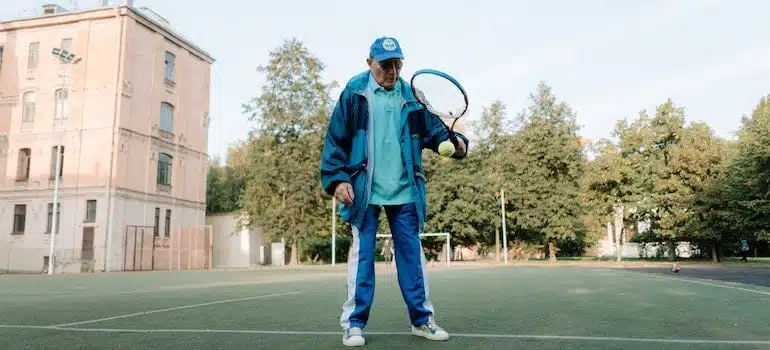 An older man holding a tennis racket, since one of the bestMiami neighborhoods for sports enthusiasts is Coconut Grove.