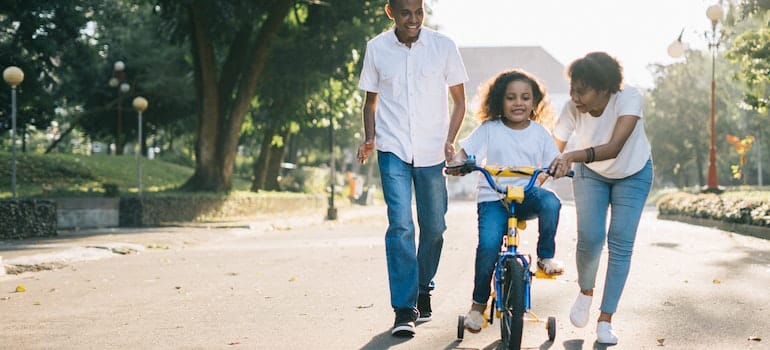 A family spending time together with their kid driving on a bicycle.