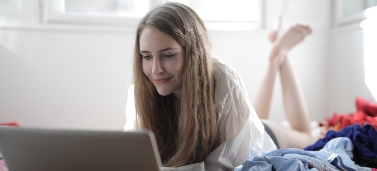 A girl in a messy room looking at laptop