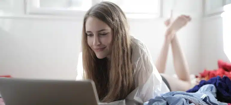 girl in messy room looking at laptop