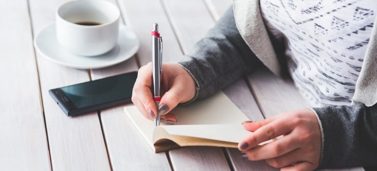 A woman writes in a notebook.