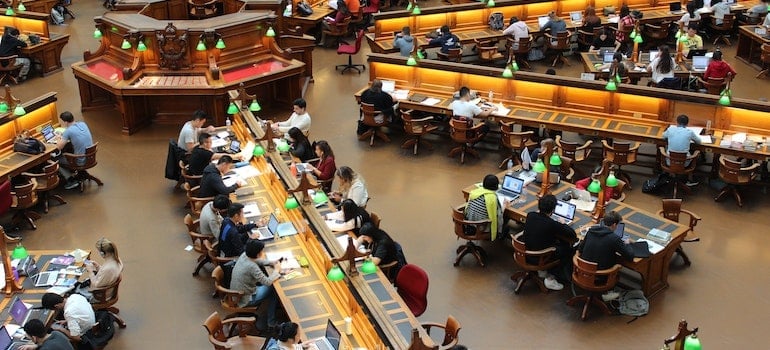 Students are sitting in a library and studying.
