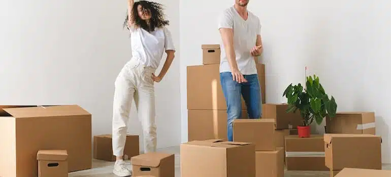 Joyful young couple dancing while they unpack china glassware and heirlooms after a move.