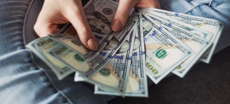 Person holding 100 US dollar banknotes