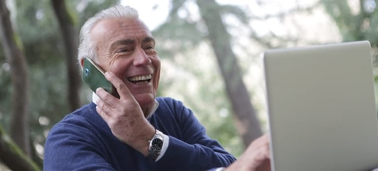 Man in blue long sleeve sweater using cellphone