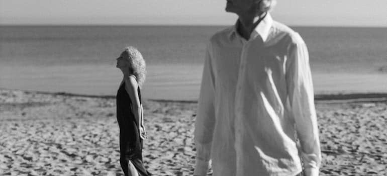 Grayscale photo of an old couple on the beach.