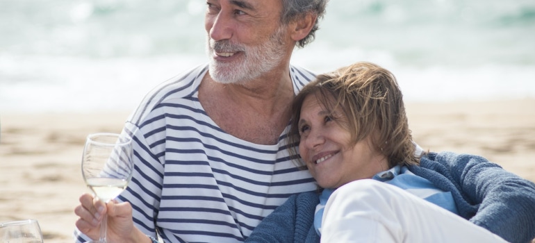 An elderly couple relaxes on the beach.