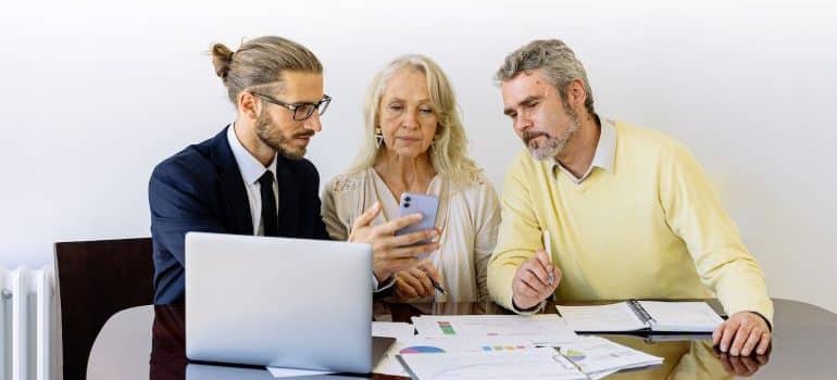 a man and two elderly people looking at papers discussing about how movers simplify an office relocation in Davie