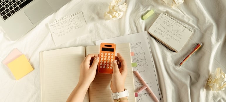 a person holds an orange calculator to budget for an interstate move this spring