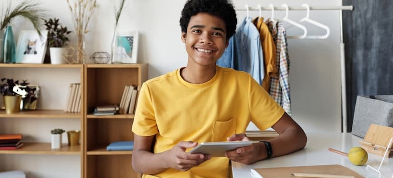 a boy in a yellow T-shirt sitting at the study desk