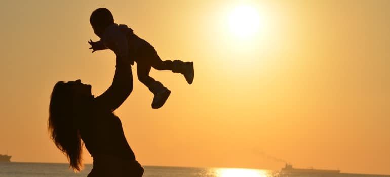 A mother playing with her baby during sunset