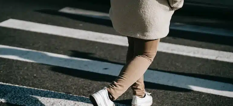 Crop faceless woman walking on zebra