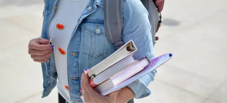 A female student holding the books while thinking about settling into college life away from Florida
