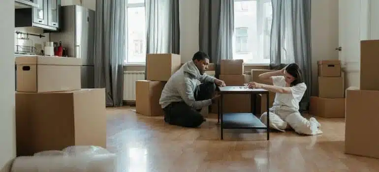 a couple assembling furniture realizing why it's not safe to move a three-bedroom apartment on your own
