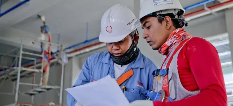 Two men wearing uniforms holding a paper and talking