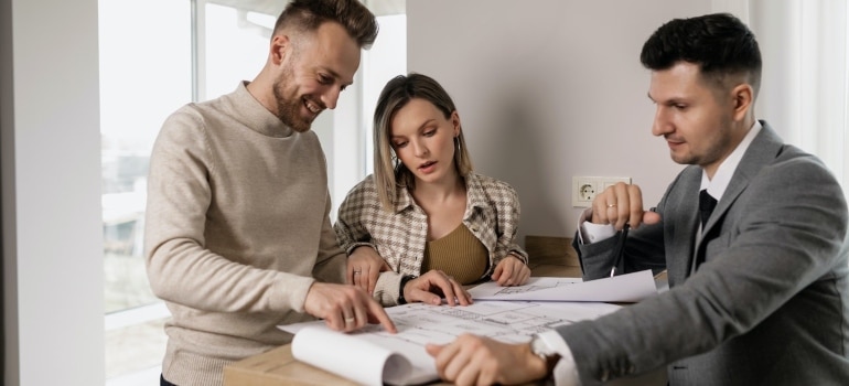 A real estate agent showing a house plan to a couple