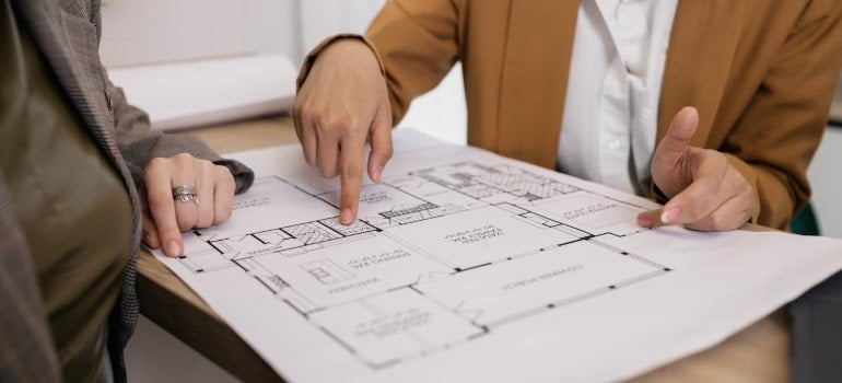A person pointing out at a home floor plan