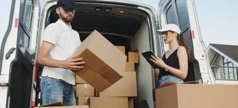 Two people surrounded by boxes discussing the details about moving luxury items