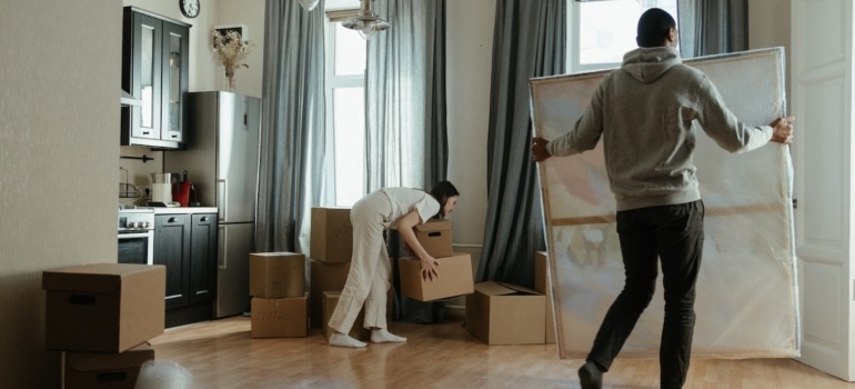 A couple packing for the last-minute art move; a man carrying a painting