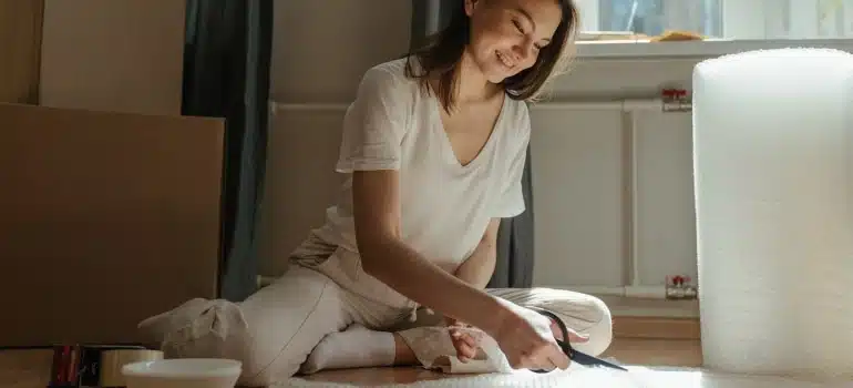 A woman cutting bubble wrap for packing paintings and canvases