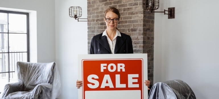 A real estate agent holding a sign "for sale"