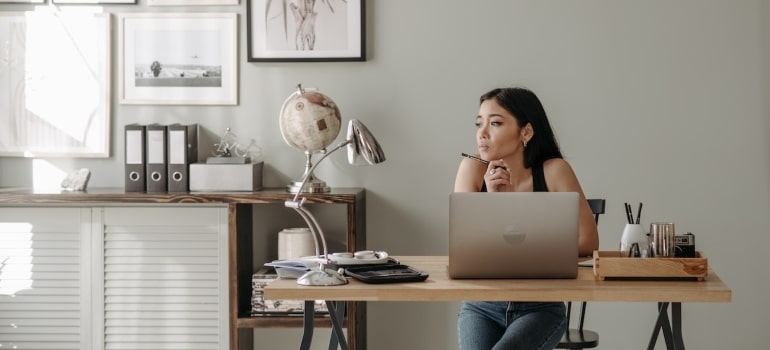 A woman sititng at her desk thinking about finding office space in Miami before the move