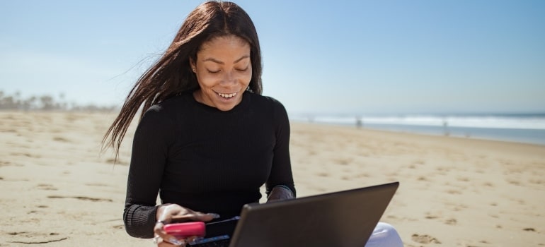 A wonan with a laptop on a beach searching for the best Florida island communities