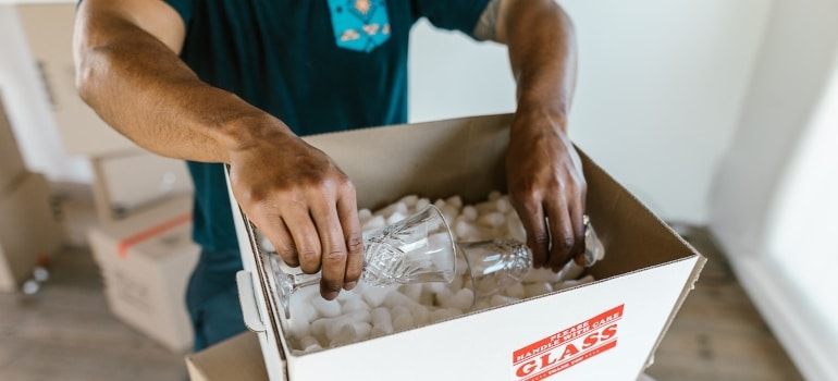 a mover packing a glass into the box from his moving company - the best way to get durable moving supplies