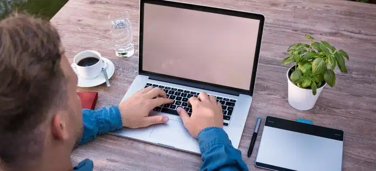 a man typing on laptop searching info about what is it like to live in Coral Gables