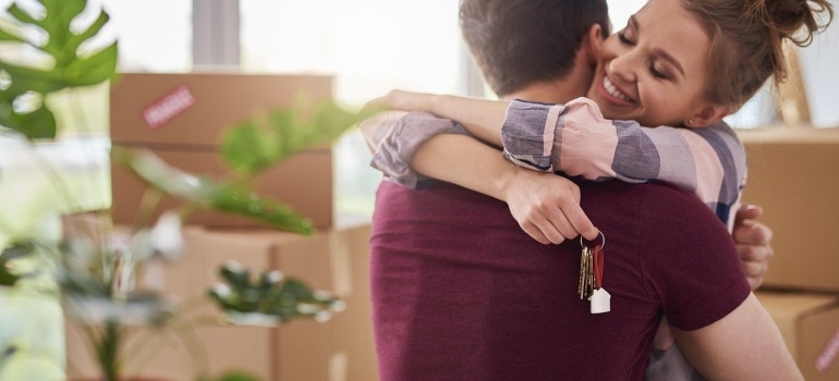 a couple hugging, surrounded by boxes, and about to live in Coral Gables